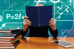 man with books and chalkboard with math