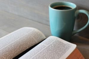 Bible on table next to coffee in teal mug